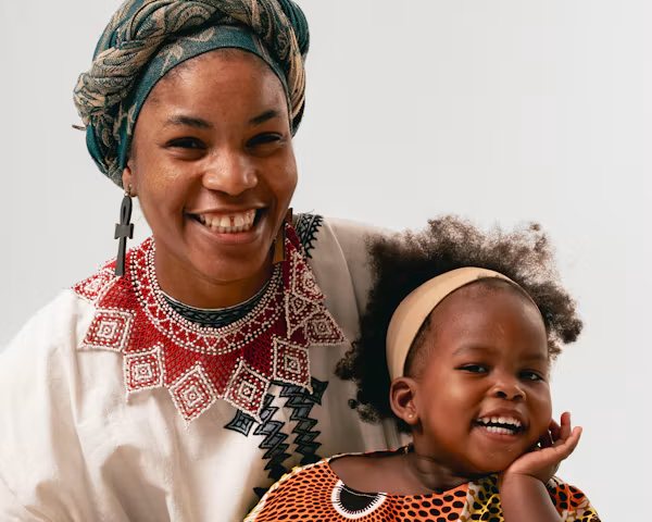 A smiling woman in a white top holding a laughing toddler